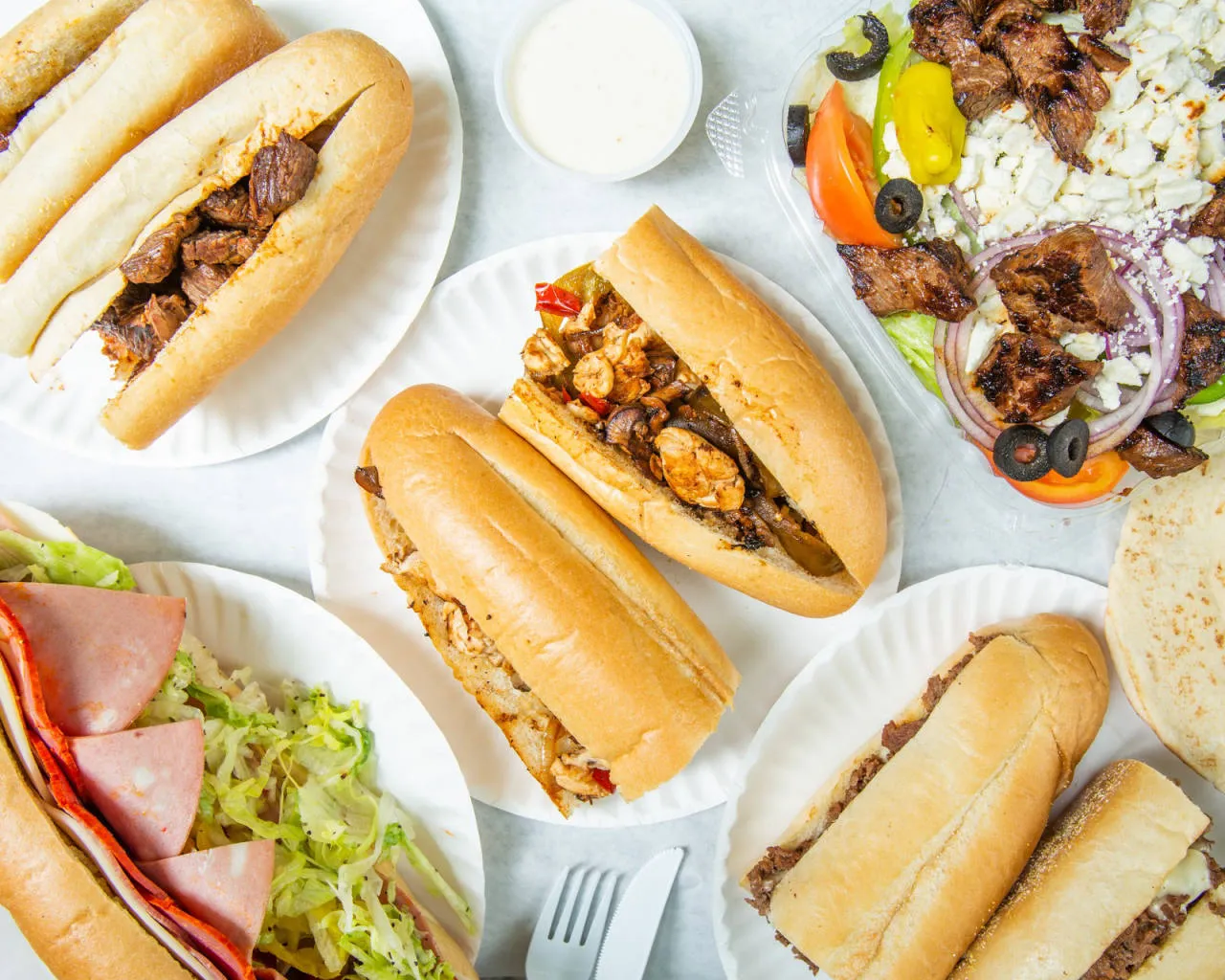 A spread of Ashmont Market subs, steak tips and a Greek salad